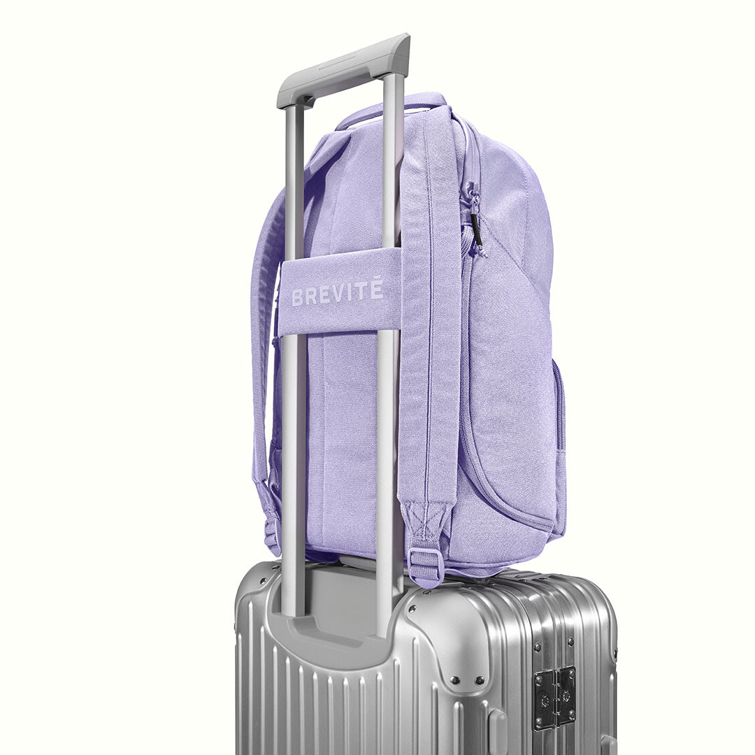 The Brevitē Backpack in Lavender Dream, luggage strap over a suitcase handle