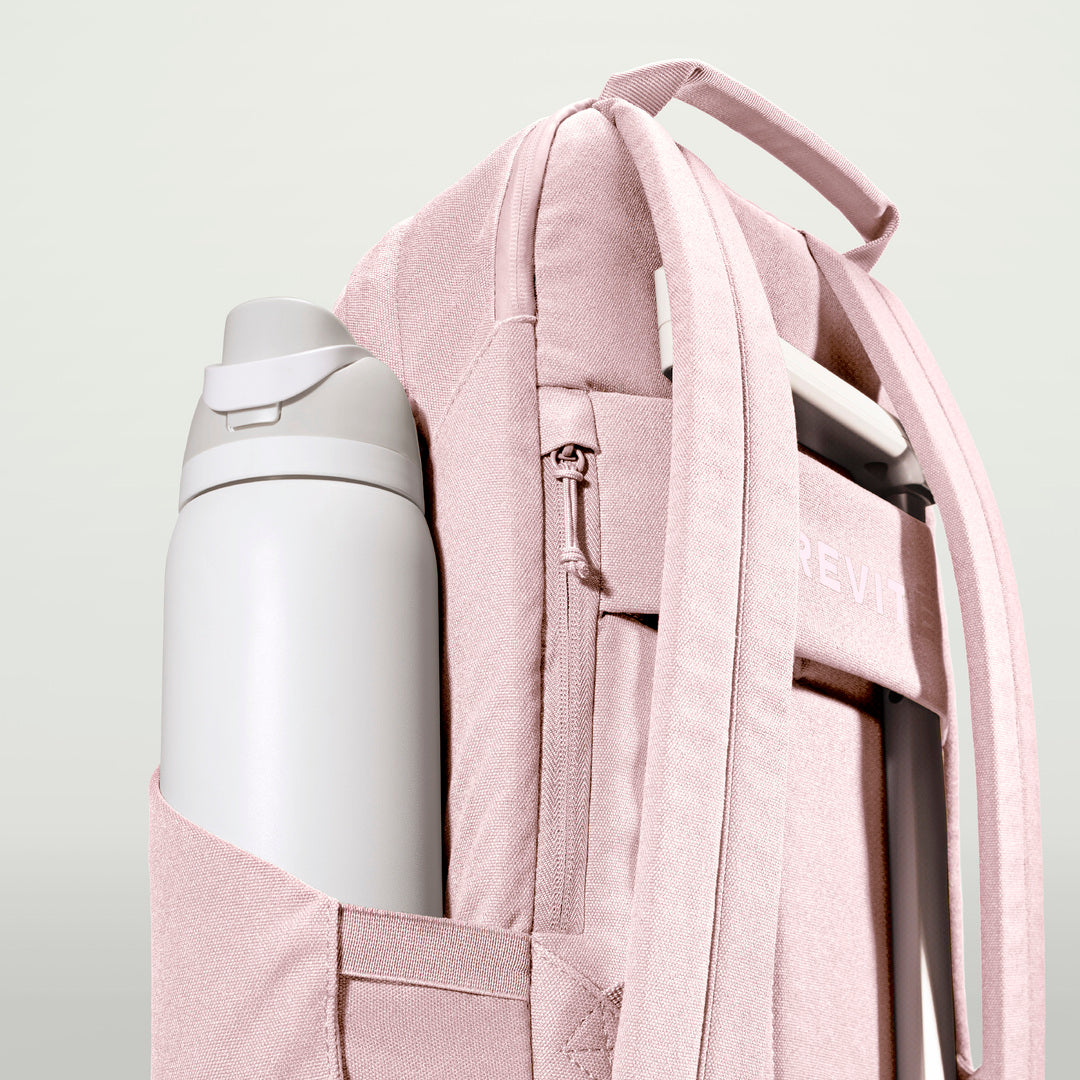 The Brevitē Backpack in Blush Pink, large water bottle in the side pocket