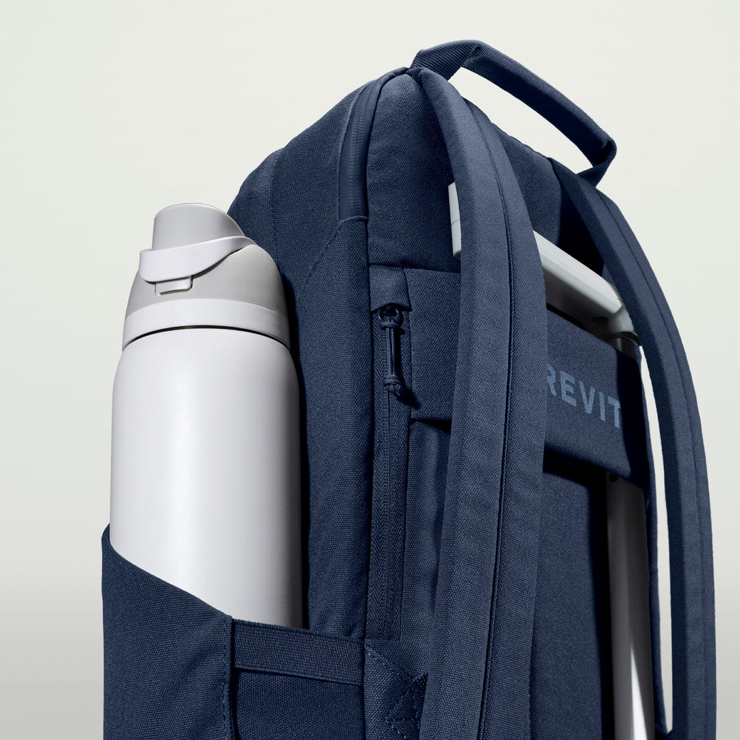 The Brevitē Backpack in Moonlit Blue, large water bottle in the side pocket