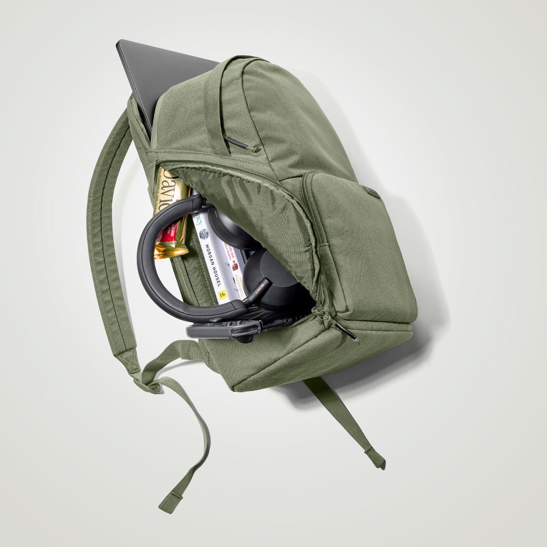 The Brevitē Backpack in Pine Green, open and packed with a laptop and everyday things