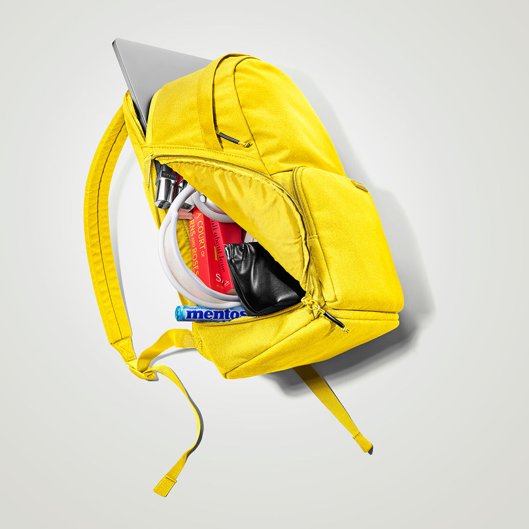The Brevitē Backpack in Lemon Yellow, open, showing the pockets