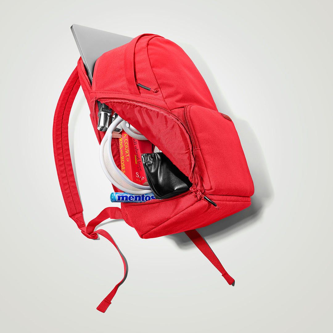 The Brevitē Backpack in Poppy Red, open, showing the pockets