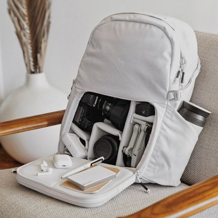 A Nimbus Gray Jumper open on an armchair, packed with a camera, lenses and a drone