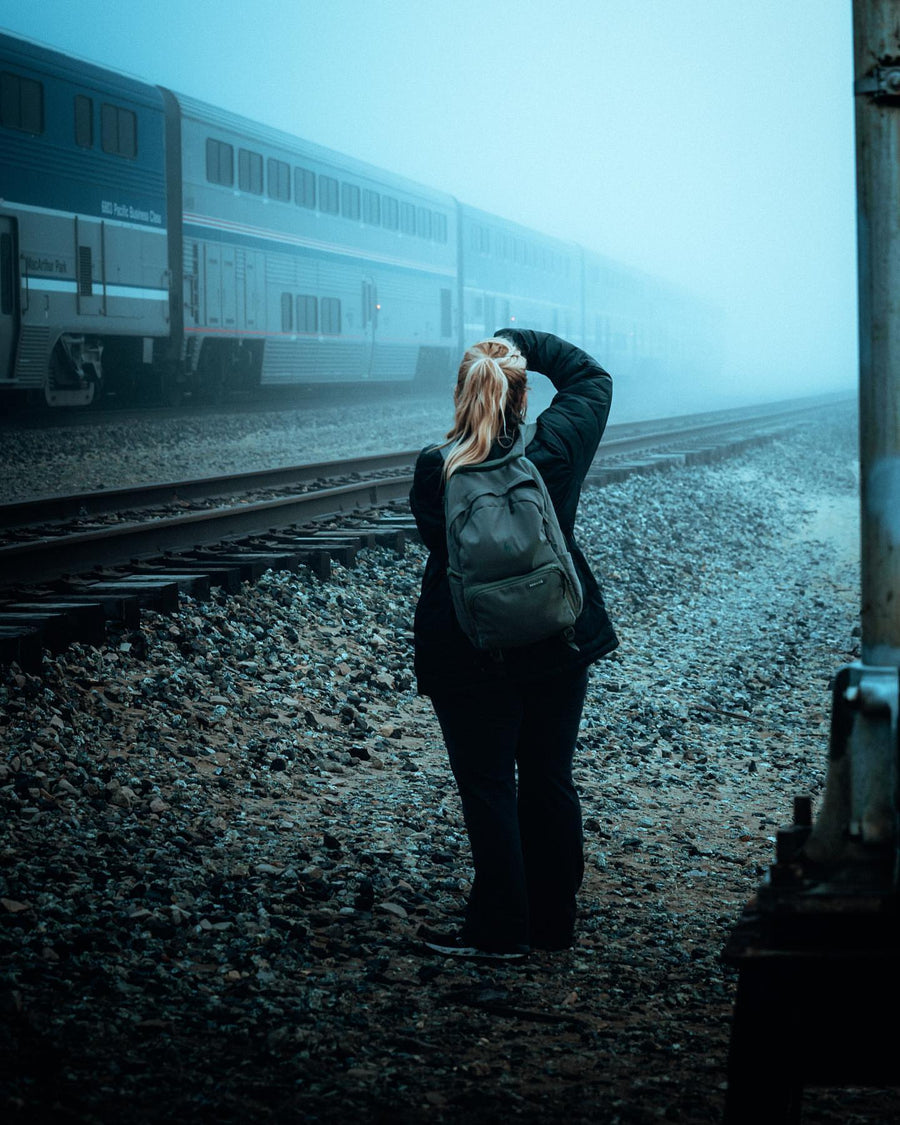 A photographer with a green Brevitē backpack shooting a passing train in thick fog