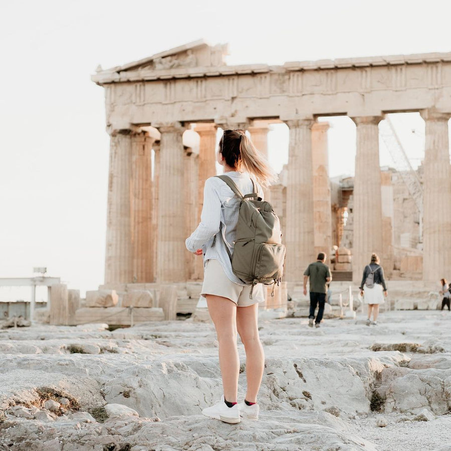 A woman with a green Brevitē backpack standing in front of the Parthenon